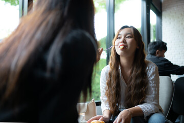 Young asian woman sitting in cafe and drinking coffee with friends.