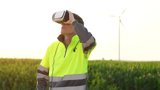 Engineer wearing virtual reality glasses in the field of wind turbines