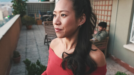 Close-up of young woman talking, in the background on the terrace his friends