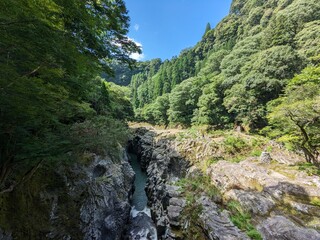 Takachiho Gorge, a narrow chasm cut through the rock by the Gokase River and partway along the gorge is the 17 meter high Manainotaki waterfall cascading down to the river below