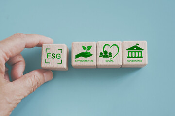For ESG Concepts on Environment, Society and Governance, hand hold green ESG Text and on wooden...