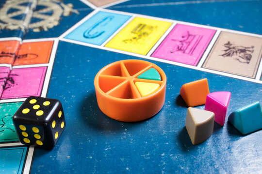 London, UK - 07 April 2019: A board games tournament - Close-up of classic board game Trivial Pursuit with black die and colored plastic pieces of different colors