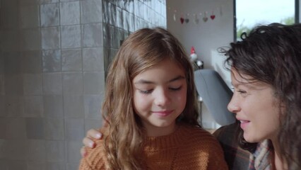 Mother kissing daughter decorating christmas presents