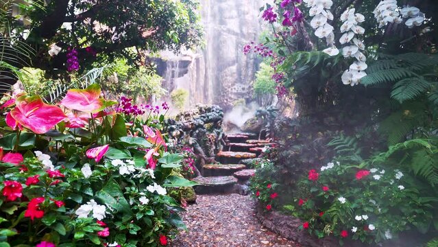 Stepping stones and wet path in blossoming garden leading to waterfall.