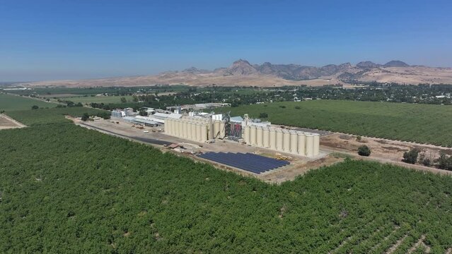 Aerial Sutter California rice elevator drying facility pull. Economy based on farming rice, grains, walnuts peaches and cattle ranch. Fields act as wetlands for waterfowl and birds.