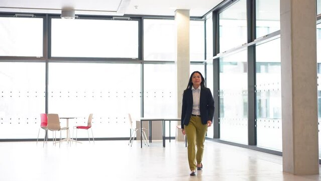 Confident businesswoman strides through hallway with determination