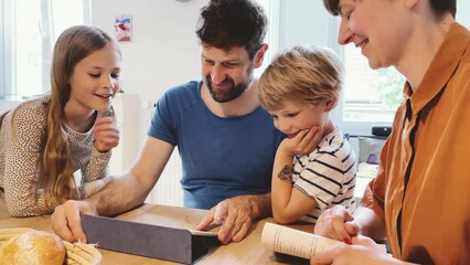 Happy familyat home using digital tablet in kitchen