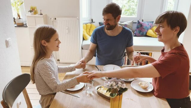 Happy family having breakfast holding hands at table