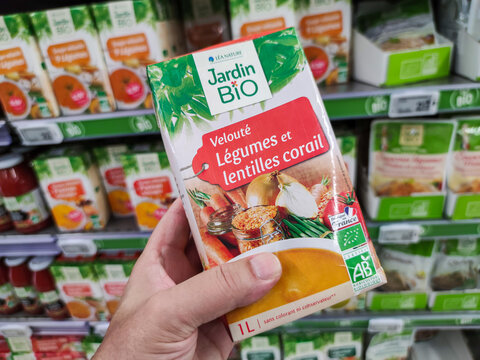 Closeup of customer hand holding an Organic Vegetable Soup with vegetables and red lentils by"Jardin bio" French brand