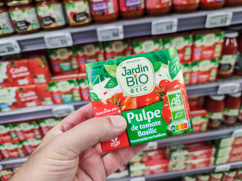 Closeup of customer hand holding a Can of Organic Tomato pulp with basil by"Jardin bio" French brand, on French Supermarket Shelf