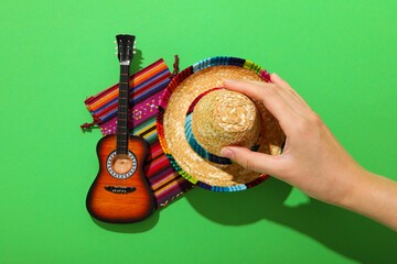 Mexican carpet, guitar and sombrero on green background.