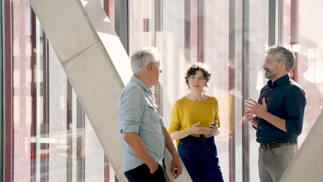 Colleagues talking relaxed during a break at office corridor