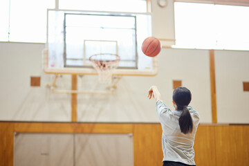 体育館でバスケットボールの練習をするスポーツウェアを着た日本人女性