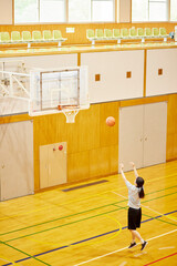 Obraz premium 体育館でバスケットボールの練習をするスポーツウェアを着た日本人女性