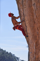 Strong man climbing rocky mountain