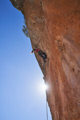 Unrecognizable woman climbing steep cliff