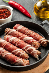 Pork wrapped in bacon in pan on a dark background. vertical image. top view. place for text