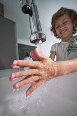 Content boy washing hands in bathroom