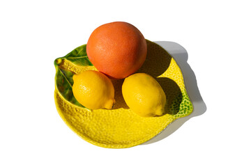 A beautiful lemon-shaped plate with an orange and two lemons, white background with copy space.