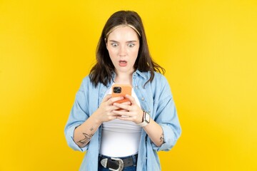 Surprised Beautiful woman wearing casual clothes using smartphone reading social media news, or...