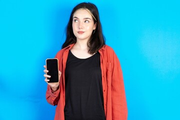 MODEL holds new mobile phone and looks mysterious aside shows blank display of modern cellular