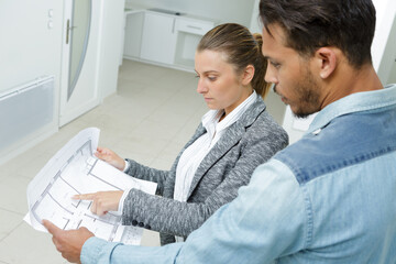 man and woman hold a project plan in the building