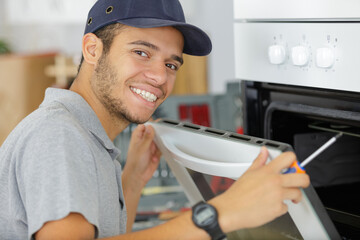 portrait of young serviceman fitting electric oven