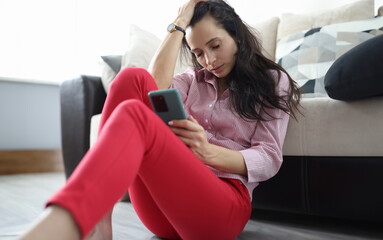 Sad woman sits on floor with closed eyes with smartphone in her hand. Signs of depression in women concept