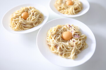 On table are three plates of spaghetti carbonara with poached yolks. Traditional Italian food...