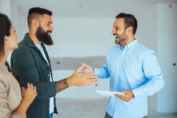 Happy couple buying a new home and handshaking with their real estate agent. Estate Agent Greeting...