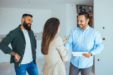 Male real estate agent showing an apartment for sale to a young couple. Real Estate Agent Shows Bright New Apartment to a Young Couple. Real estate agent selling house to a young couple