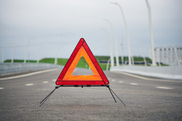 Red emergency stop sign on road line. Red triangle. Breakdown triangle stands alongside the road. Car broke down sign on road concept.