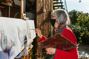 Senior woman painting on canvas in garden