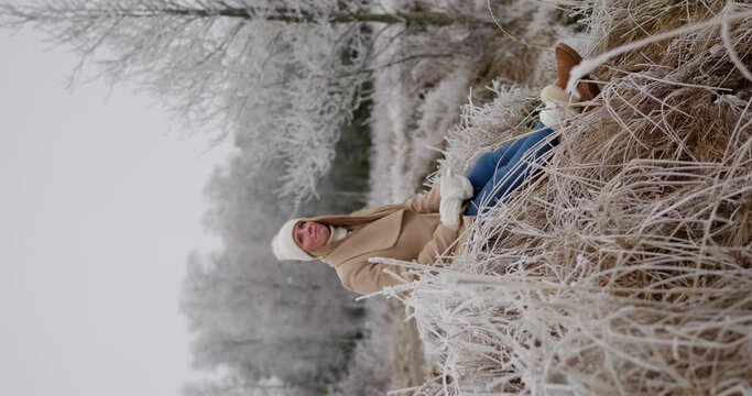 Young pretty woman drinking tea enjoying winter frozen nature by the sea