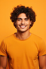 Fototapeta na wymiar Portrait of a smiling young handsome male, with curly brown hair and an orange T-shirt, on an orange background