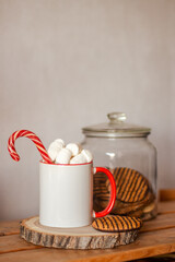 Christmas or New Year mockup of mug. White and red mug with candy cane, marshmallows and cookies. Template for mug design

