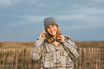 Anonymous smiling female teenager talking on smartphone in nature