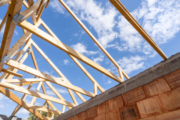 Wooden roof with support joist, boards and timber planks against blue sky