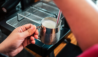 Professional barista warming milk for cappuccino. hand of Barista using the coffee machine for coffee latte