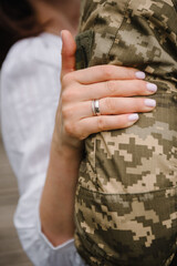 War and love. Engagement. Wedding rings. Brave soldier embracing wife before leaving. Patriotic man goes serve country. Closeup husband in camouflage uniform hugging woman, finally together.