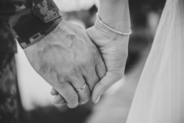 War and love. Closeup man in camouflage uniform holds hand woman. Engagement. Wedding rings. Serviceman, soldier hugs wife before leaving for war. Patriotic man go serve country. Black white photo