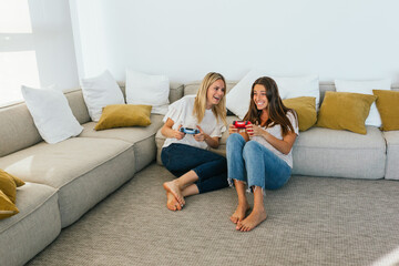 Obraz premium Cheerful women playing videogame on couch