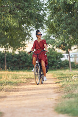 Ethnic woman riding bicycle and looking away