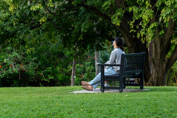 Fototapeta premium Asian couple sitting on a park bench relaxing, enjoying the gardens