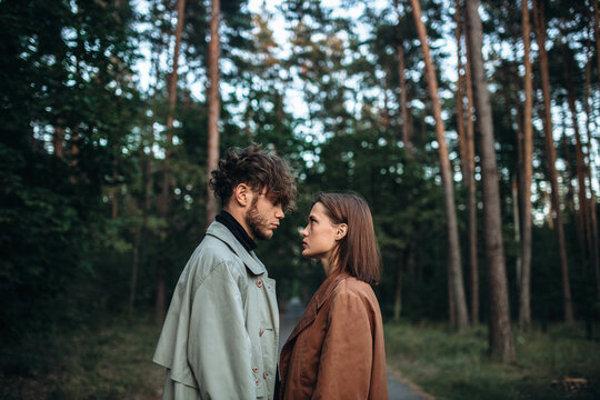 young couple in love in a fashionable coat walks through the forest. Autumn gloomy mood and a beautiful couple of models. Cinematic image