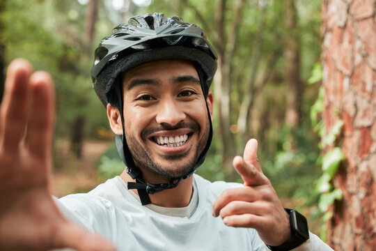 Cycling man, selfie and smile in forest, pointing and portrait for wellness, training and blog on adventure. Influencer guy, helmet and happy in profile picture, memory or live stream on social media