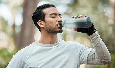 Sports, man and drinking water in park for exercise break, energy and workout rest. Thirsty athlete, asian runner and bottle for hydration, nutrition and healthy recovery of fitness in nature outdoor