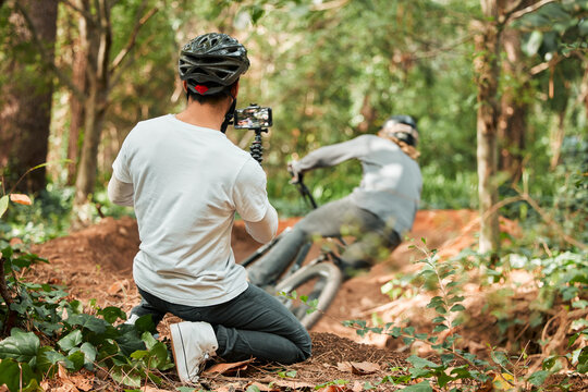 Man, bike and forest with photographer, speed and phone for race, cycling video or post on web blog. Guy, bicycle and recording for vlog, live streaming or social media in woods for outdoor sports
