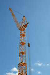 Naklejka premium Vertical Shot of Yellow Construction Crane Against Blue Sky