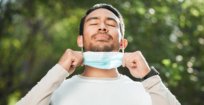 Covid, Asian man and take off mask for end of pandemic, breathing and outdoor protected. Corona, healthy guy and Japanese person remove face cover for fresh air, freedom and decrease infection rates